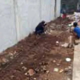 Workers clearing soil along a boundary wall
